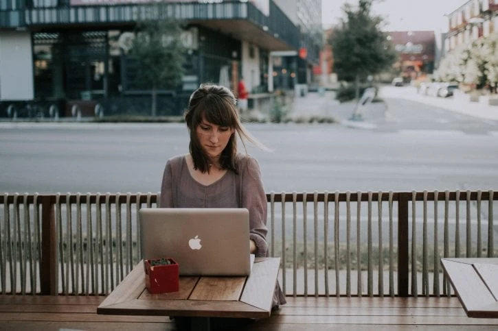 woman_in_gray_shirt_sitting_on_bench_in_front_of_MacBook woman in gray shirt sitting on bench in front of MacBook